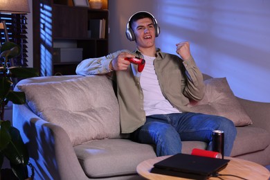 Emotional man playing video games with controller at home