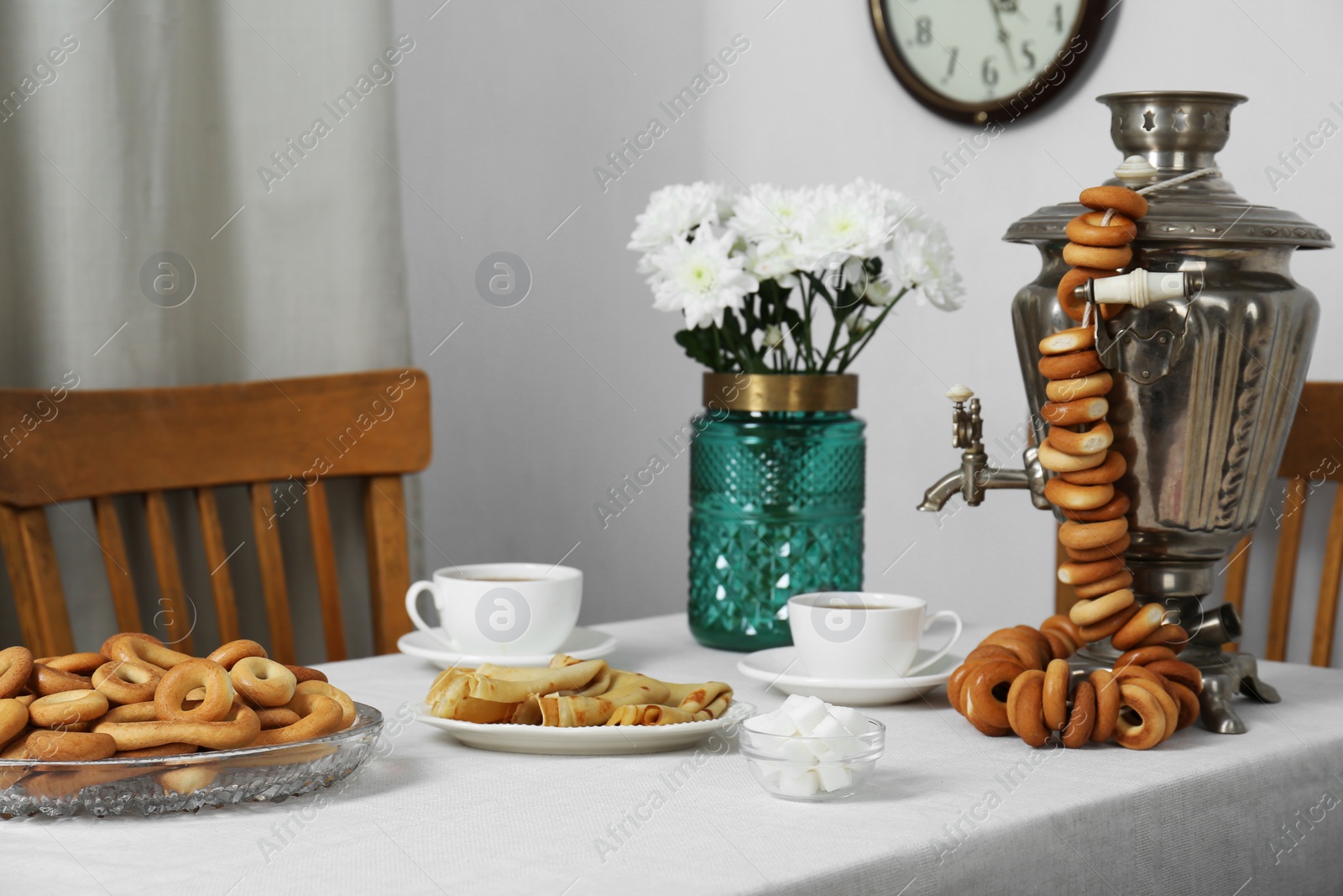 Photo of Vintage samovar, cup of hot drink and snacks served on table indoors. Traditional Russian tea ceremony