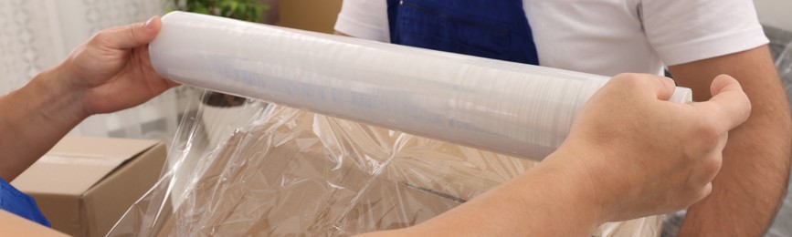 Image of Workers wrapping box in stretch film indoors, closeup. Banner design