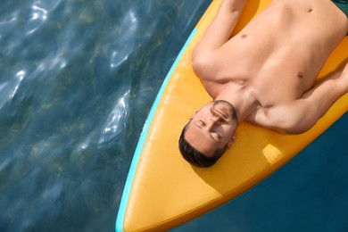 Photo of Man lying on SUP board in sea, top view. Space for text