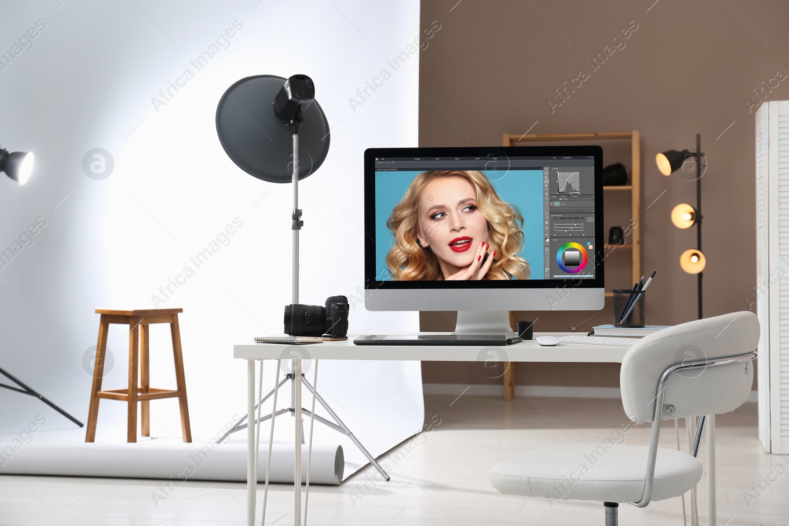 Photo of Retoucher's workplace. Computer with photo editor application, camera and graphic tablet on table in studio