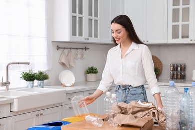 Photo of Smiling woman separating garbage in kitchen. Space for text