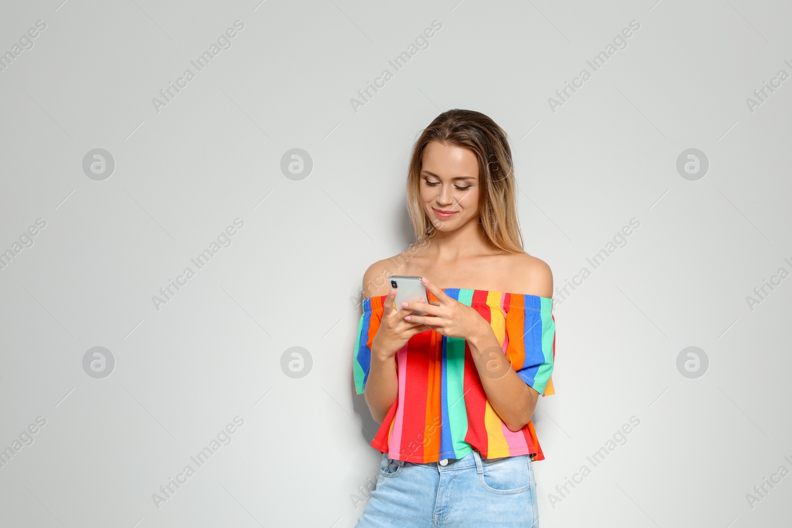 Photo of Portrait of beautiful woman with smartphone on light background