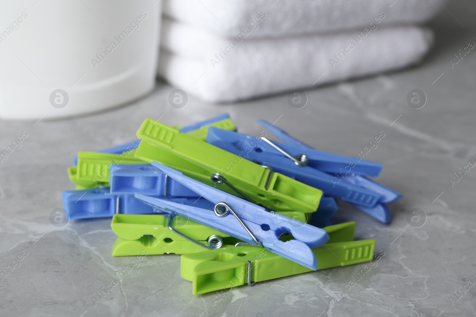 Photo of Colorful plastic clothespins on grey table, closeup