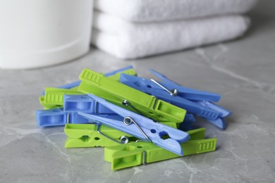 Colorful plastic clothespins on grey table, closeup