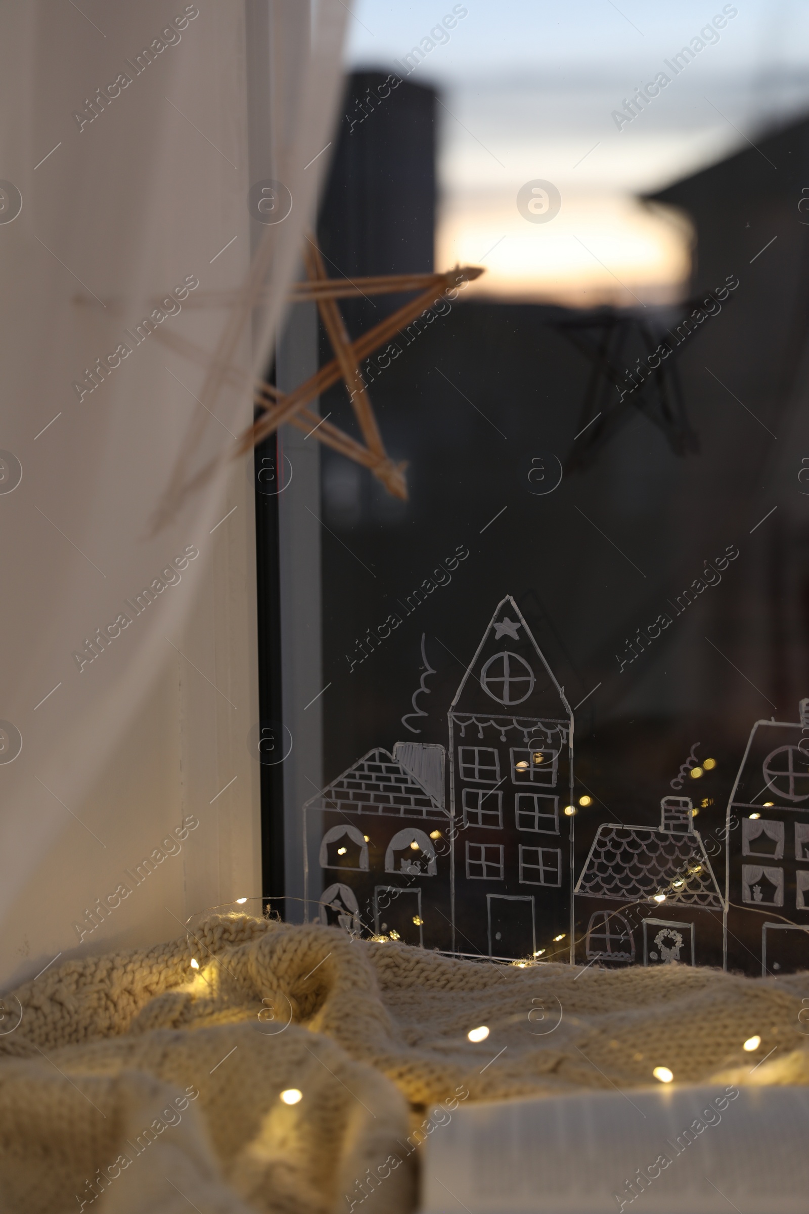 Photo of Open book and cup of hot drink on plaid near window with beautiful drawing at home. Christmas decor