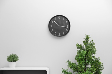 Office interior with houseplants and clock on wall. Time management