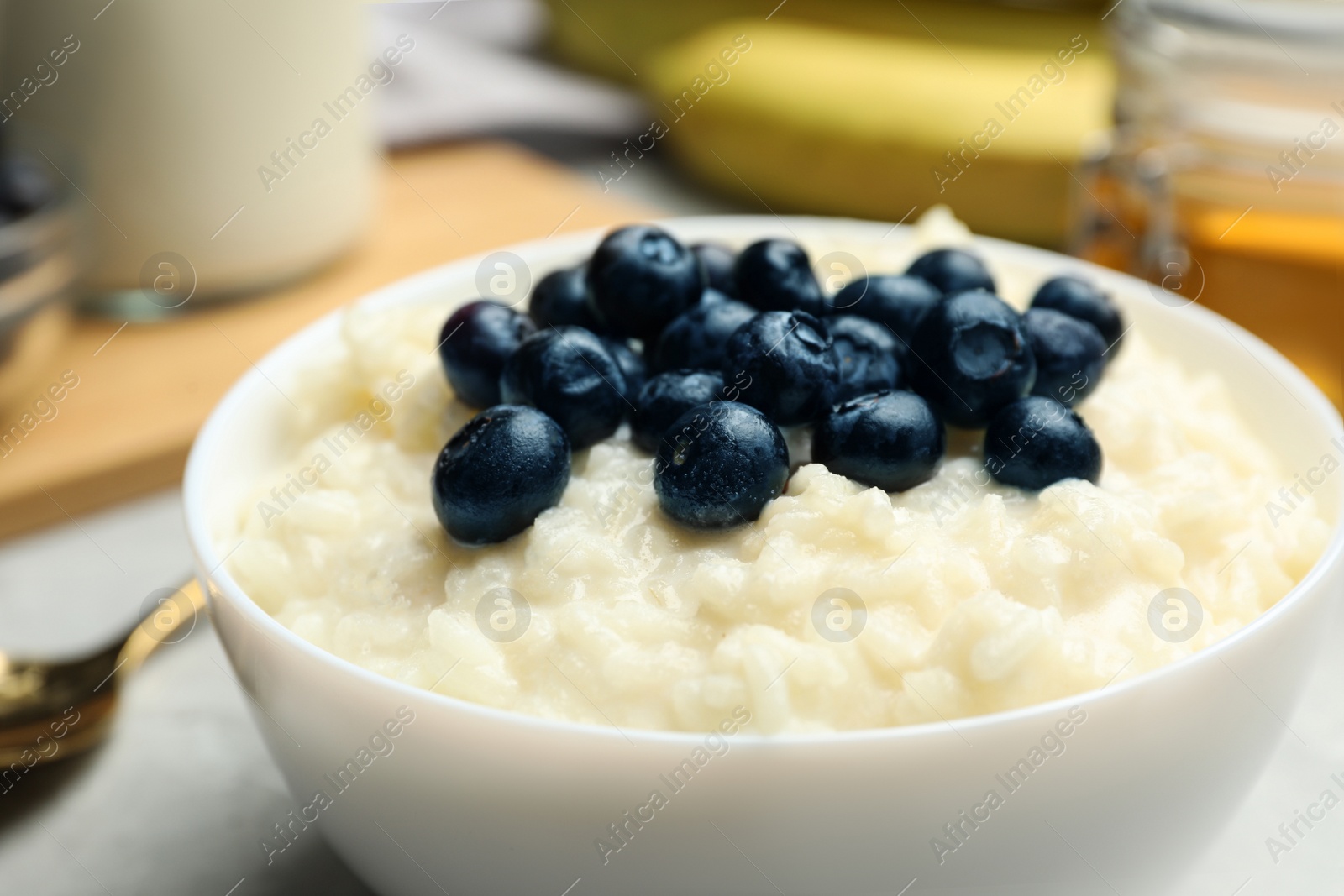 Photo of Delicious rice pudding with blueberries on table, closeup