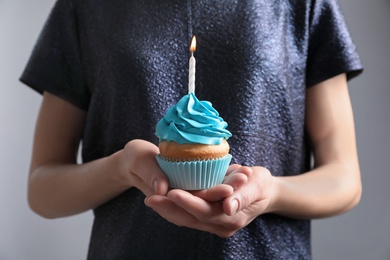Photo of Woman holding birthday cupcake, closeup