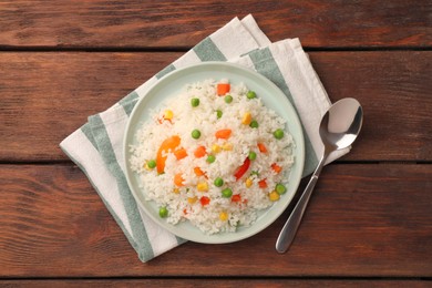 Photo of Delicious rice with vegetables and spoon on wooden table, flat lay