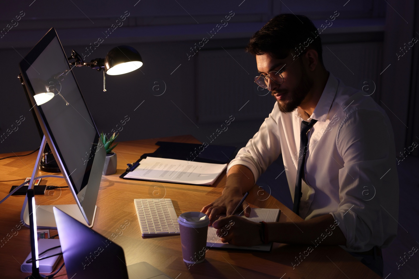 Photo of Tired young man working late in office