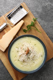 Photo of Delicious cream soup with parmesan cheese and croutons in bowl on grey table, top view