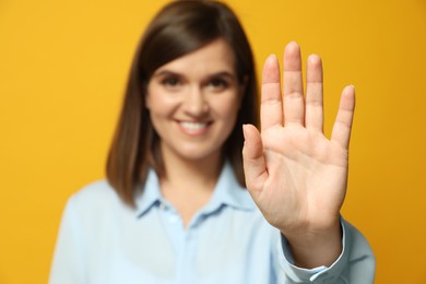 Photo of Left-handed woman against yellow background, focus on palm