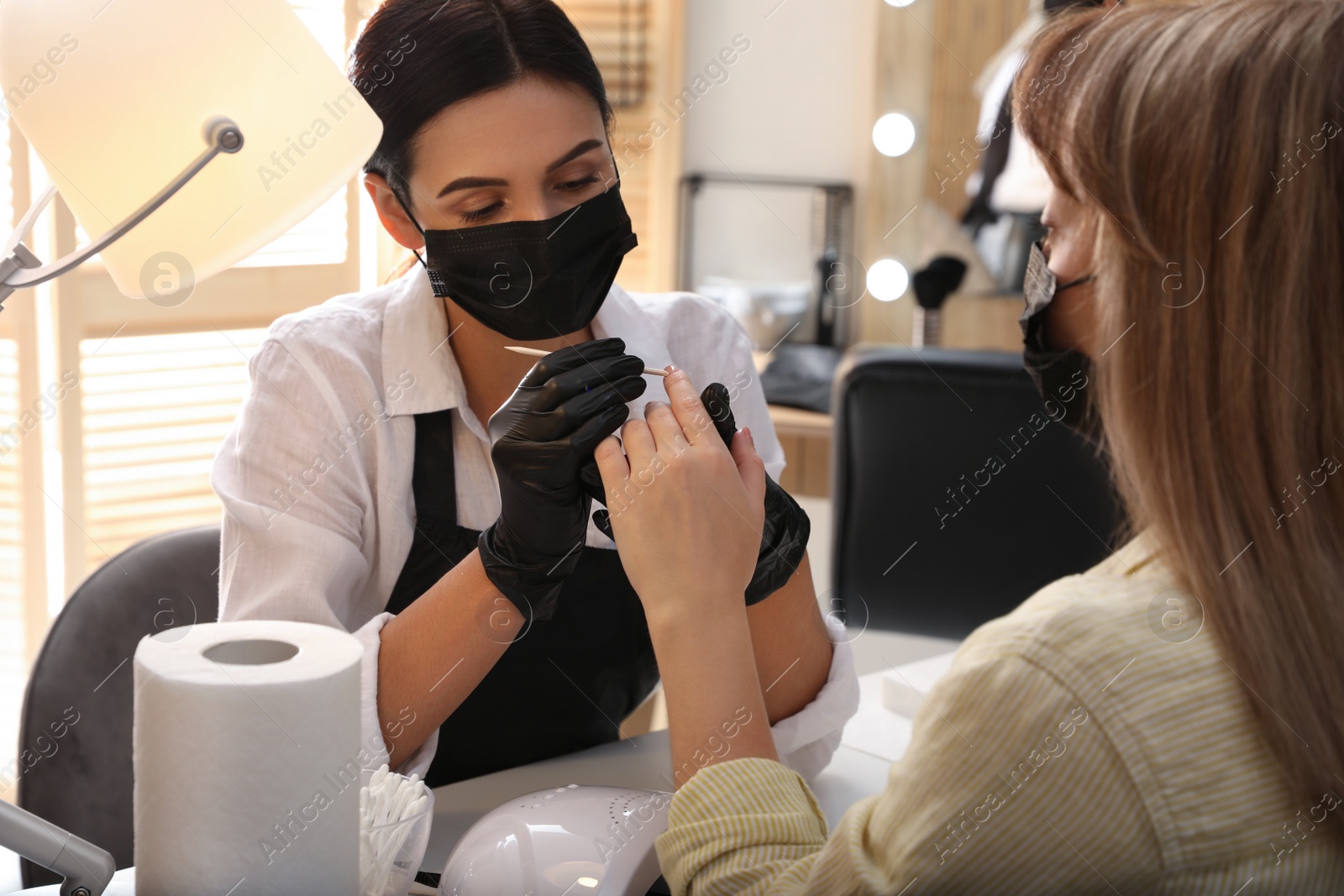 Photo of Professional manicurist working with client in salon. Beauty services during Coronavirus quarantine