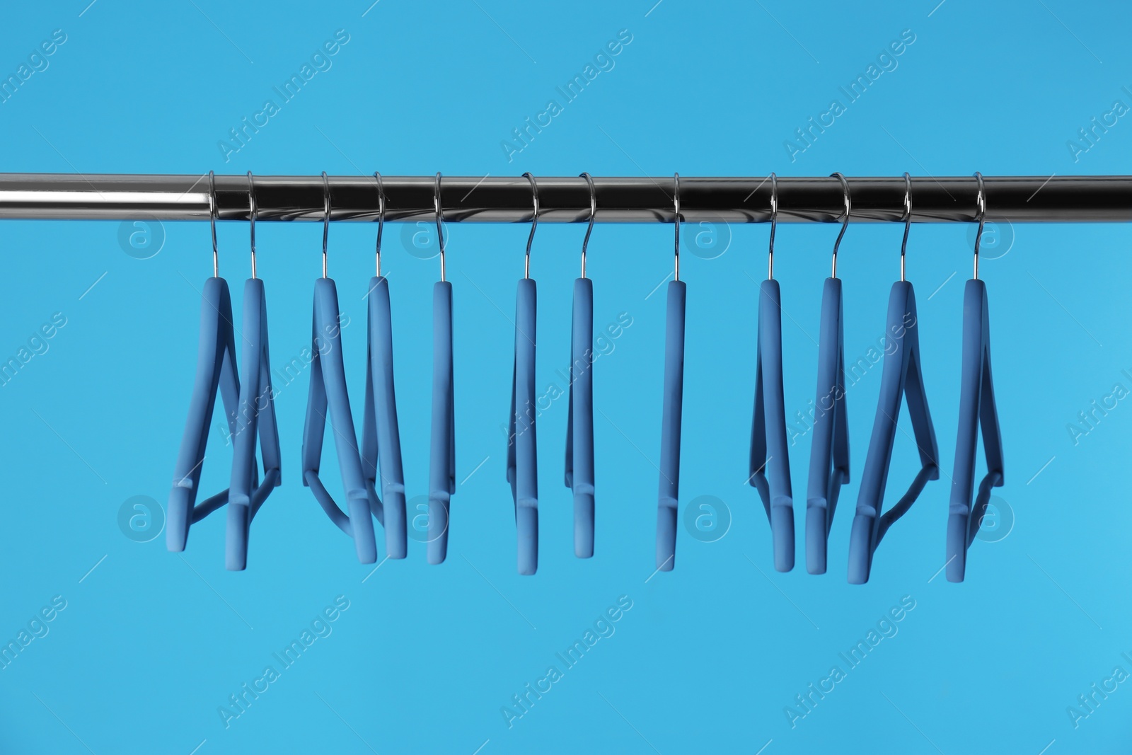 Photo of Metal rack with clothes hangers on color background