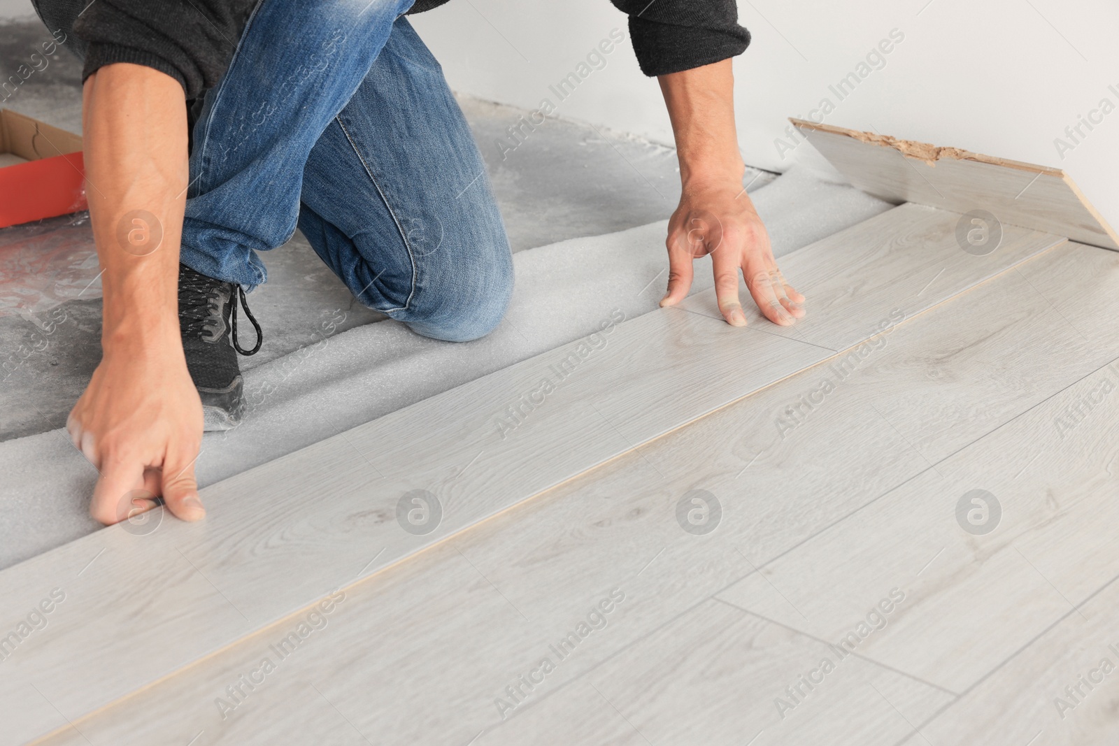 Photo of Professional worker installing new laminate flooring, closeup