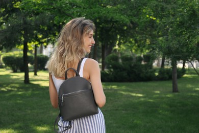 Photo of Young woman with stylish backpack in park, back view