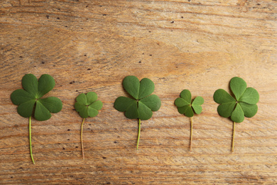 Photo of Clover leaves on wooden table, flat lay. St. Patrick's Day symbol