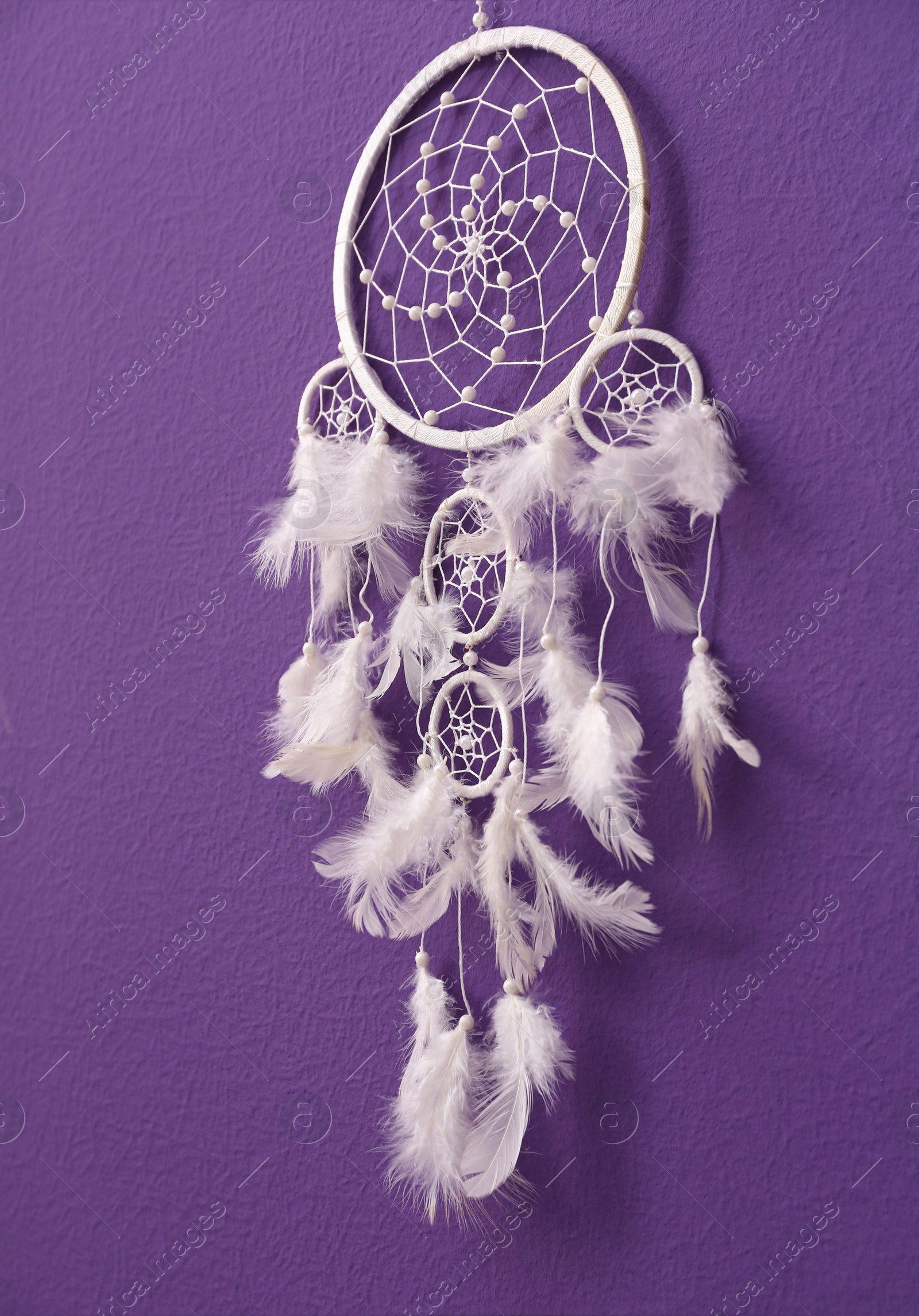 Photo of Beautiful handmade dream catcher on purple wall