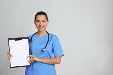 Photo of Portrait of young medical assistant with stethoscope and clipboard on color background. Space for text