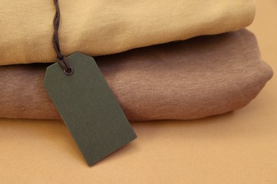 Photo of Garment with cardboard tag on kraft paper sheet, closeup. Space for text