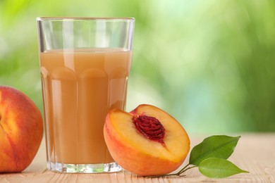 Photo of Tasty peach juice, fresh fruits and green leaves on wooden table outdoors, closeup