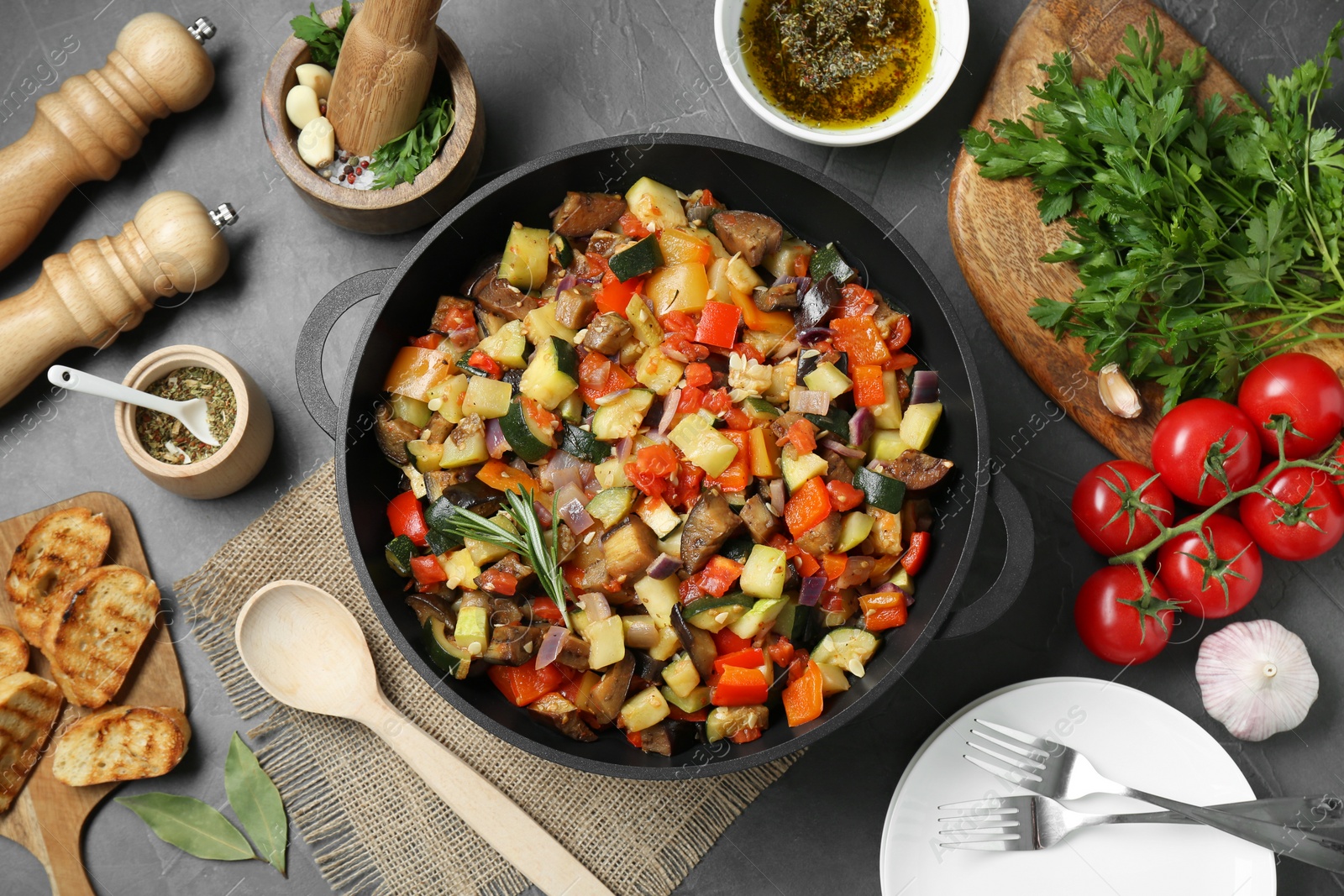 Photo of Delicious ratatouille and ingredients on grey table, flat lay