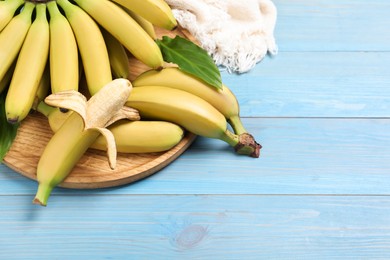 Tasty ripe baby bananas on light blue wooden table