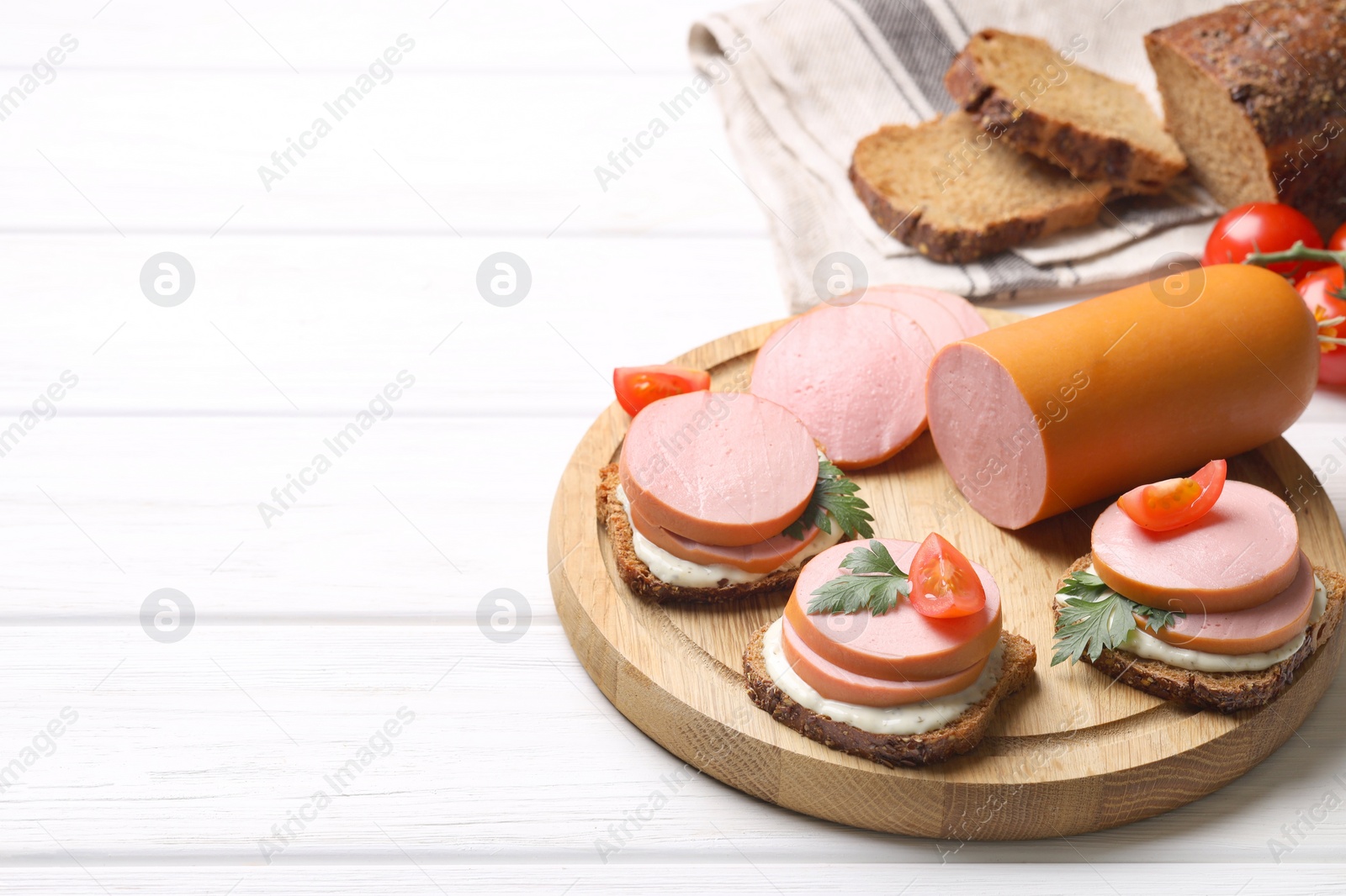Photo of Delicious sandwiches with boiled sausage, tomato and sauce on white wooden table, space for text