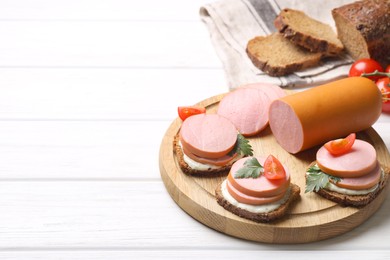 Delicious sandwiches with boiled sausage, tomato and sauce on white wooden table, space for text