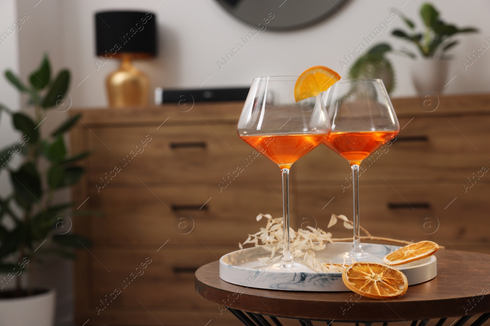 Photo of Tasty cocktail in glasses on wooden table in room, space for text. Relax at home