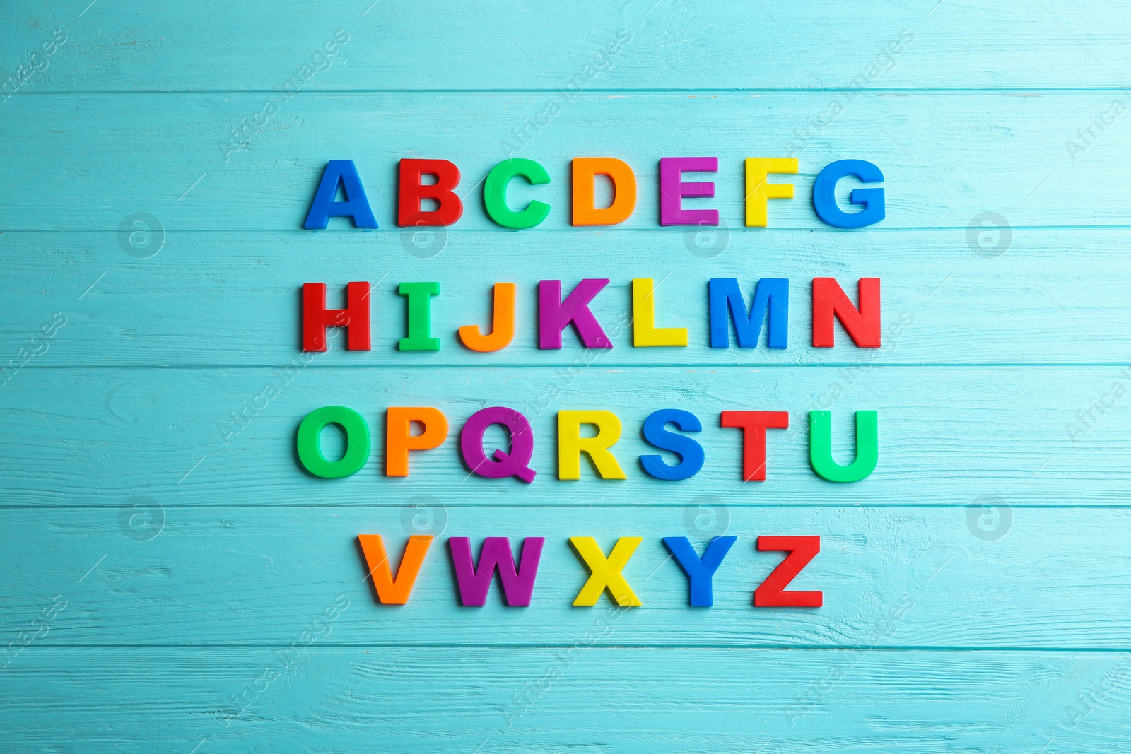 Photo of Colorful magnetic letters on light blue wooden background, flat lay. Alphabetical order