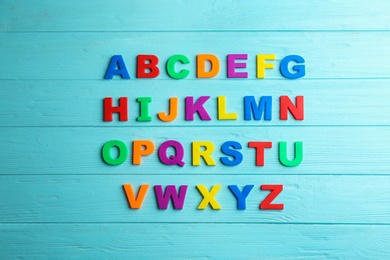 Colorful magnetic letters on light blue wooden background, flat lay. Alphabetical order