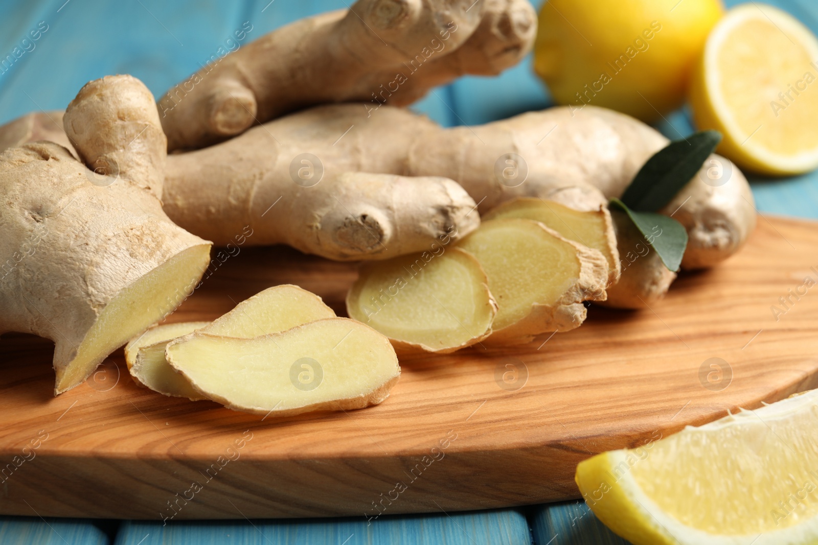 Photo of Cut ginger and lemon on wooden board, closeup