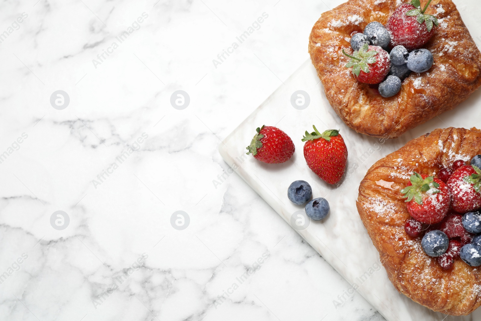 Photo of Fresh delicious puff pastry with sweet berries on white marble table, top view. Space for text