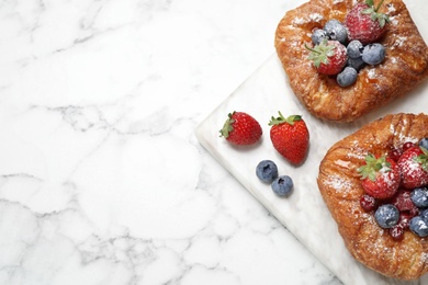 Fresh delicious puff pastry with sweet berries on white marble table, top view. Space for text