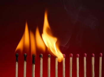 Line of burning matches on color background