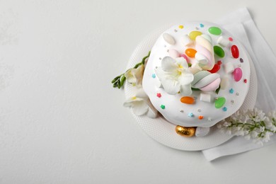Photo of Traditional Easter cake with sprinkles, jelly beans, marshmallows and decorated eggs on white table, flat lay. Space for text