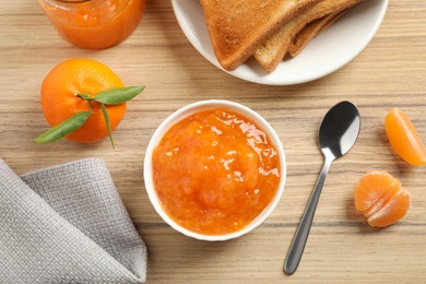 Photo of Tasty jam, toasts and fresh tangerines on wooden table, flat lay