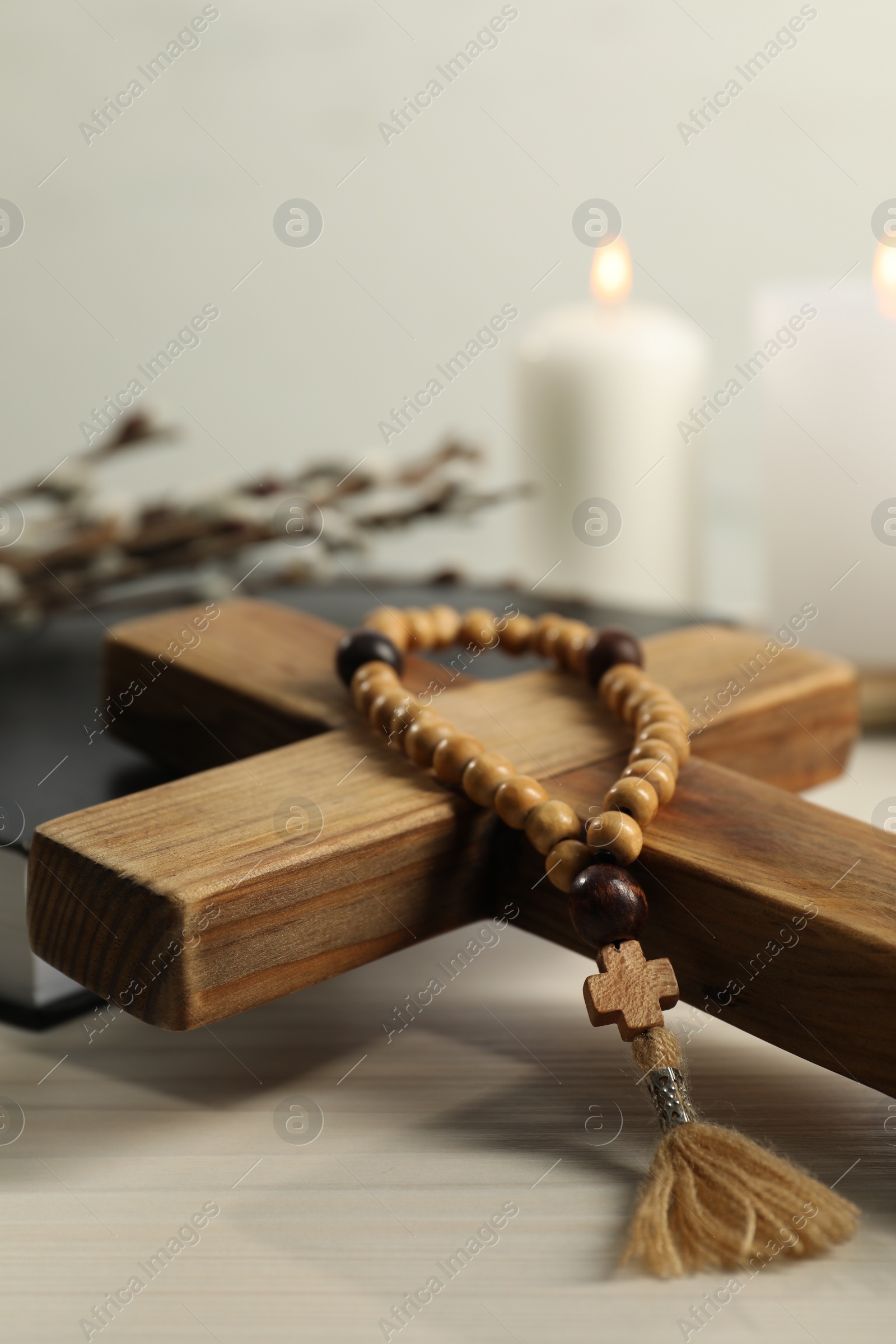 Photo of Wooden cross and rosary beads on white table, closeup