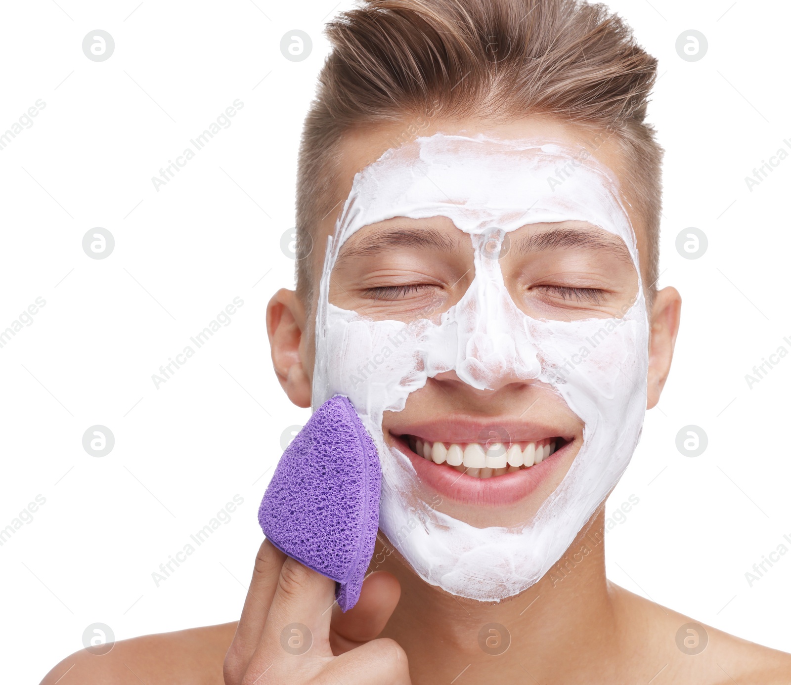 Photo of Happy young man washing off face mask with sponge on white background