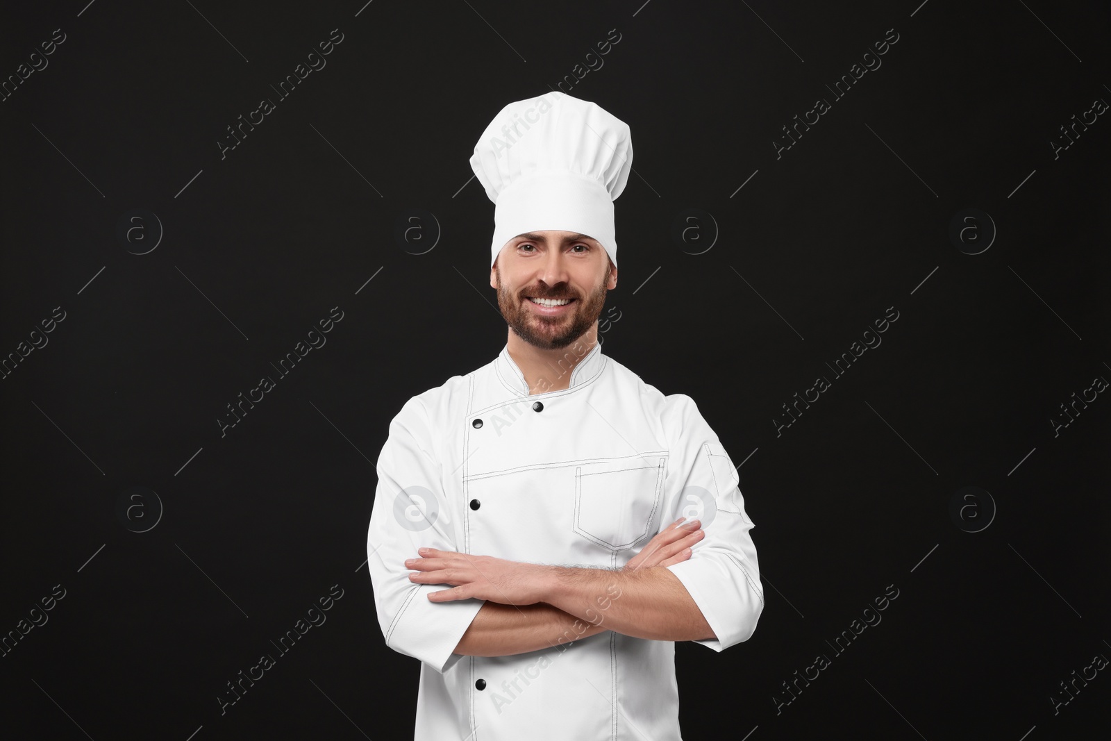 Photo of Smiling mature male chef on black background