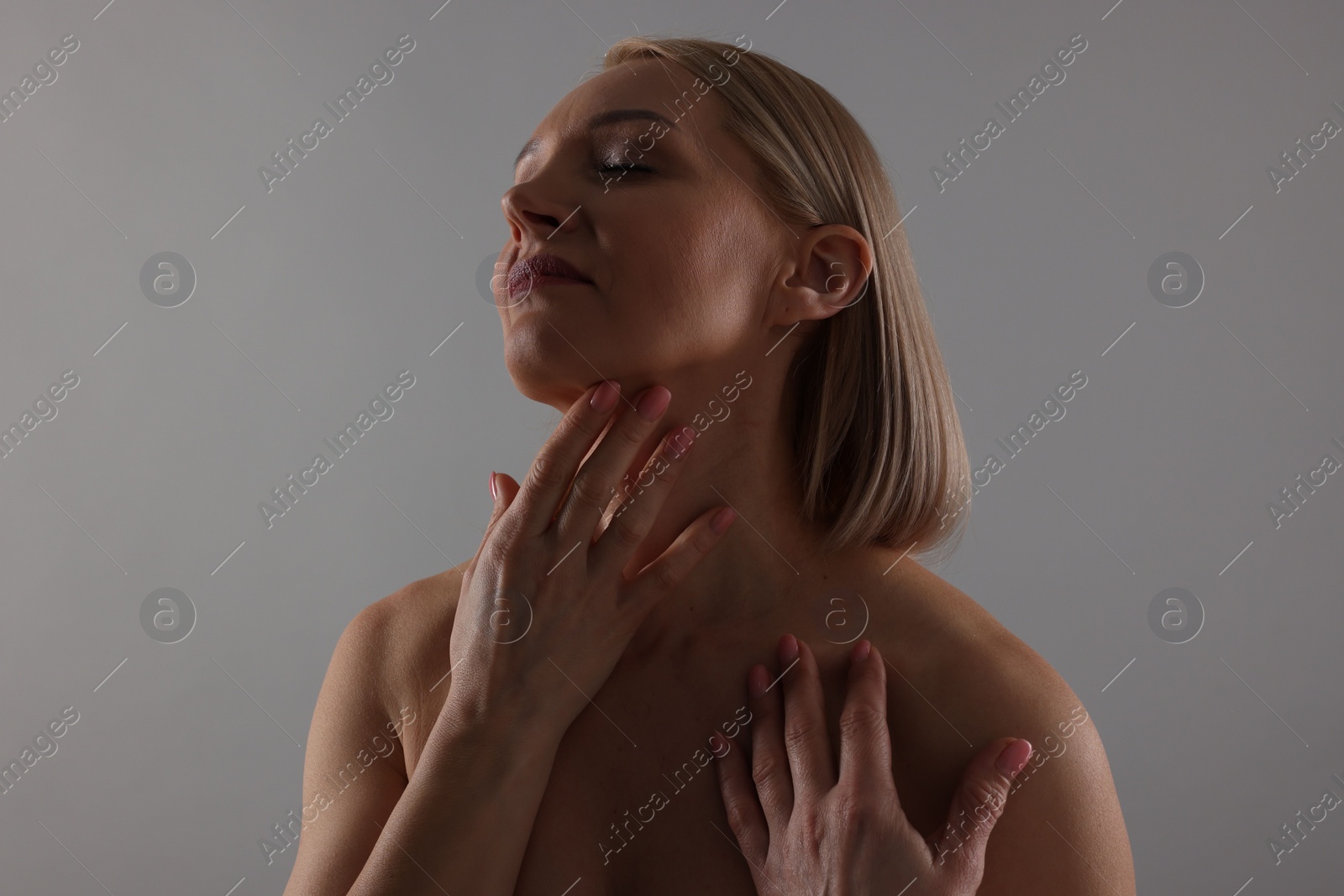 Photo of Beautiful woman touching her neck on grey background