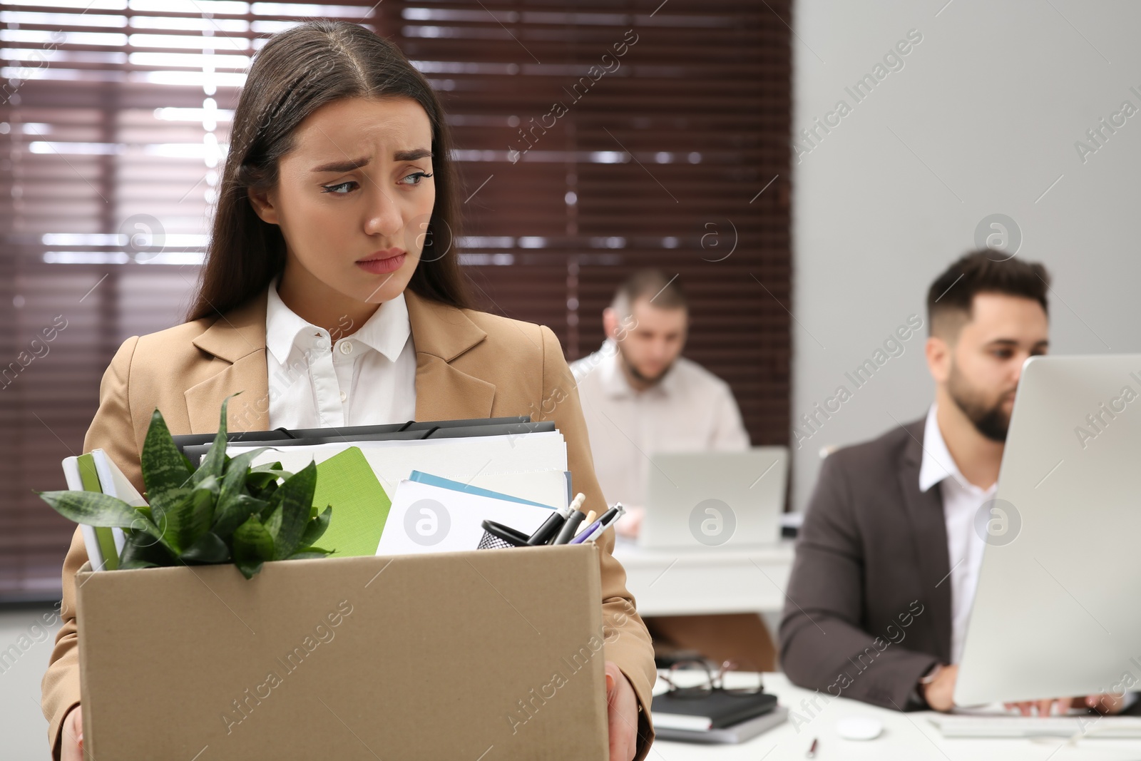 Photo of Upset dismissed woman carrying box with personal stuff in office