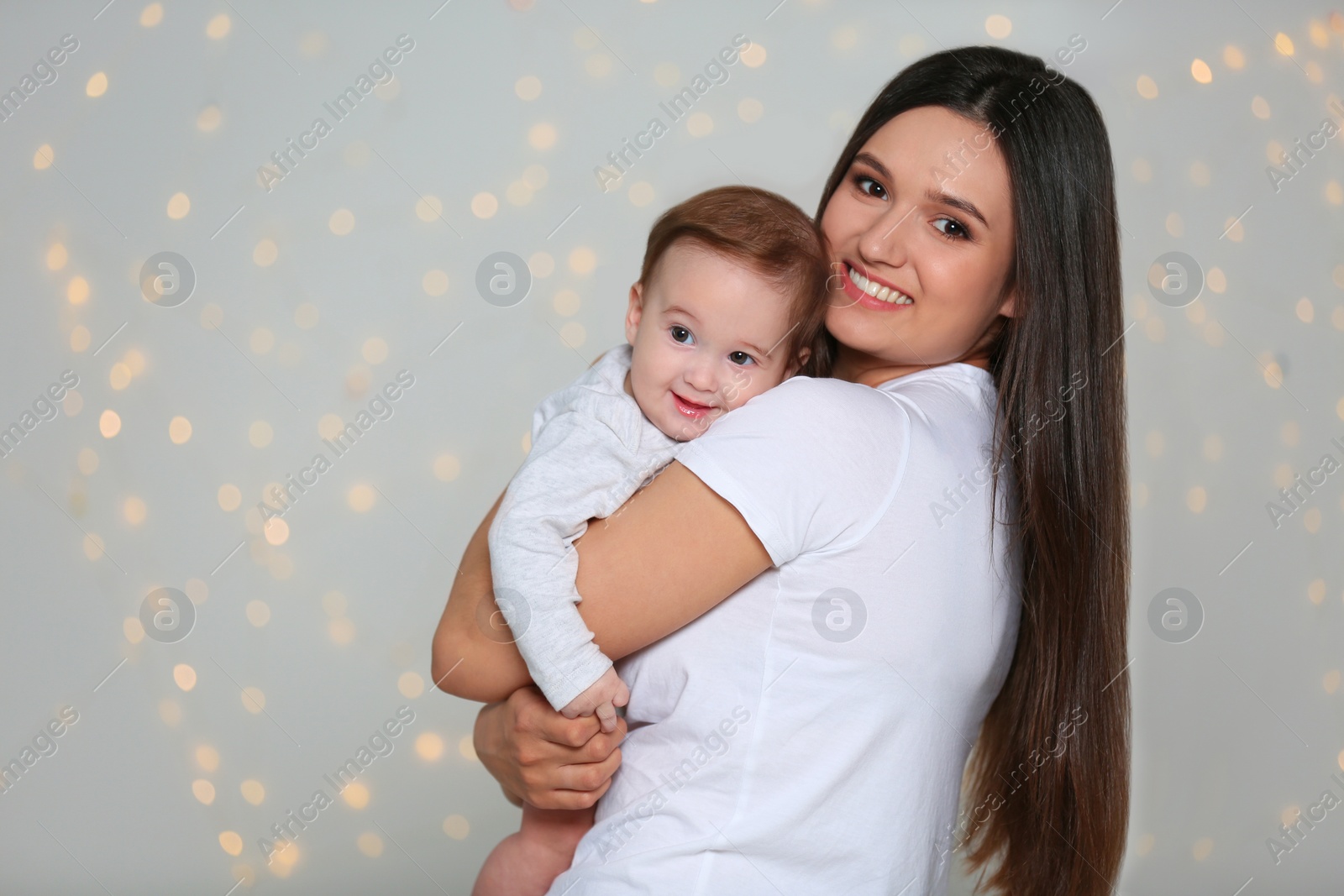 Photo of Portrait of young mother and her adorable baby against defocused lights