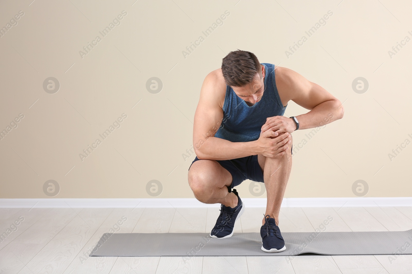 Photo of Male athlete suffering from knee pain during training indoors