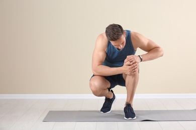 Photo of Male athlete suffering from knee pain during training indoors