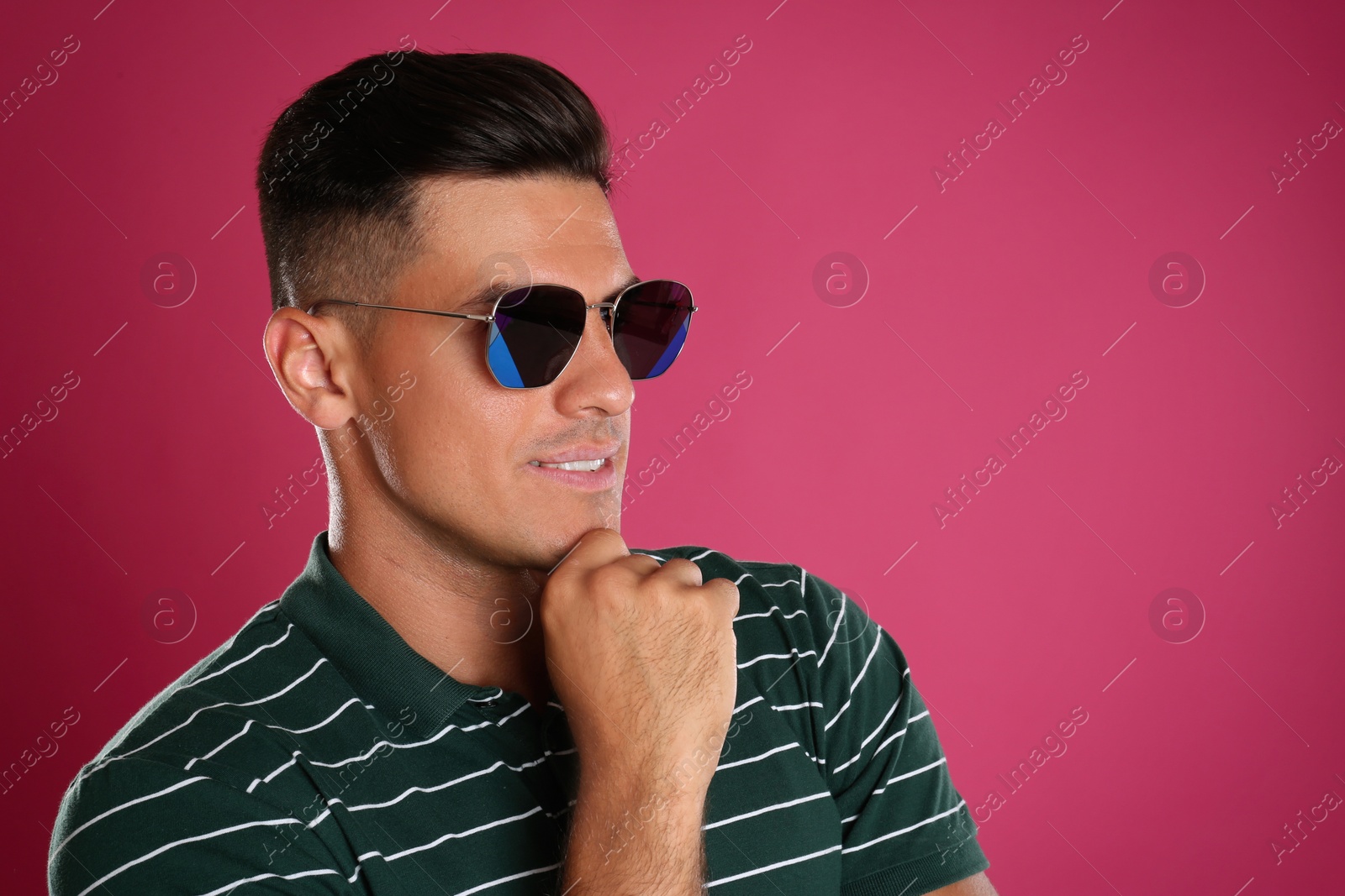 Photo of Handsome man wearing sunglasses on pink background. Space for text