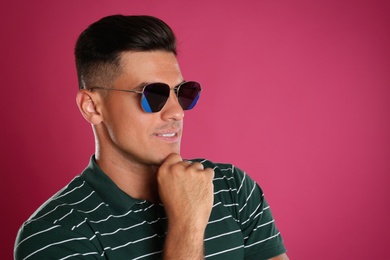 Handsome man wearing sunglasses on pink background. Space for text