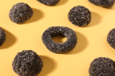 Photo of Tasty liquorice candies on yellow background, closeup